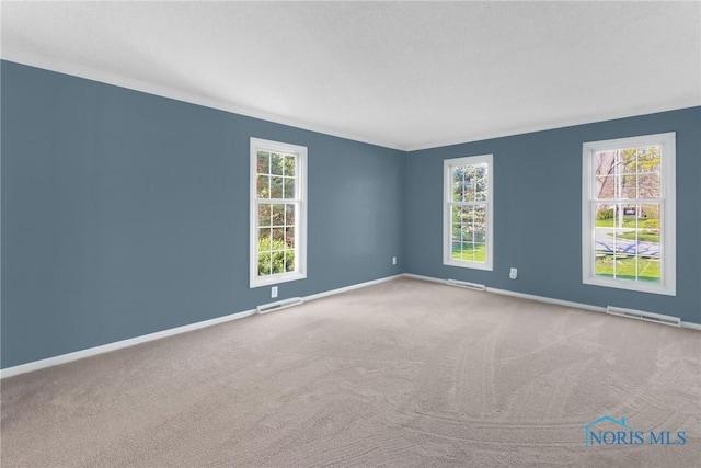empty room with visible vents, baseboards, carpet floors, and a healthy amount of sunlight