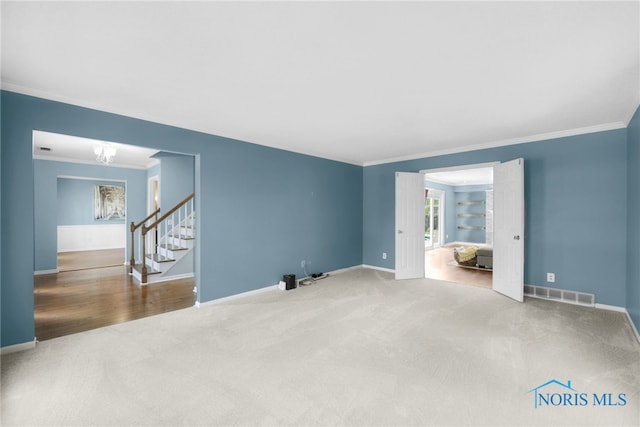 unfurnished living room with stairway, visible vents, baseboards, ornamental molding, and carpet floors