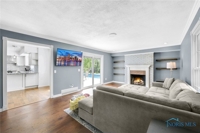 living room featuring crown molding, a textured ceiling, wood finished floors, and baseboards