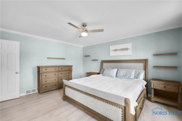 bedroom featuring wood finished floors, visible vents, crown molding, and baseboards