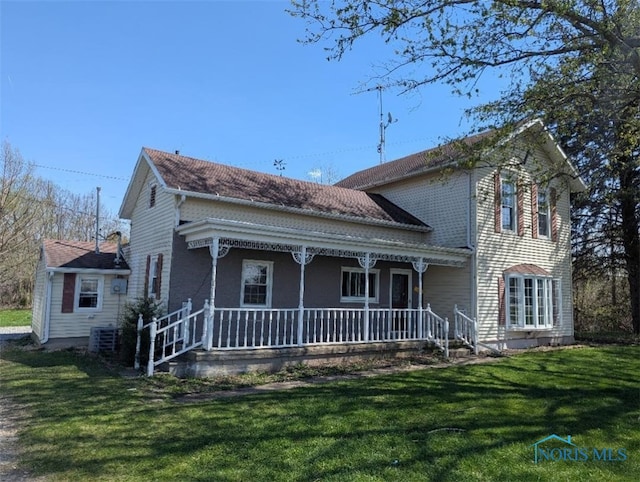 view of front of home with covered porch, a front yard, and cooling unit