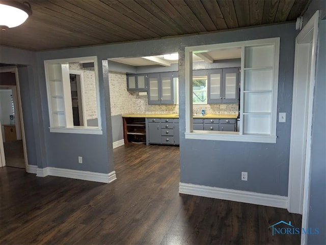 kitchen with dark wood finished floors, gray cabinetry, wooden ceiling, baseboards, and glass insert cabinets