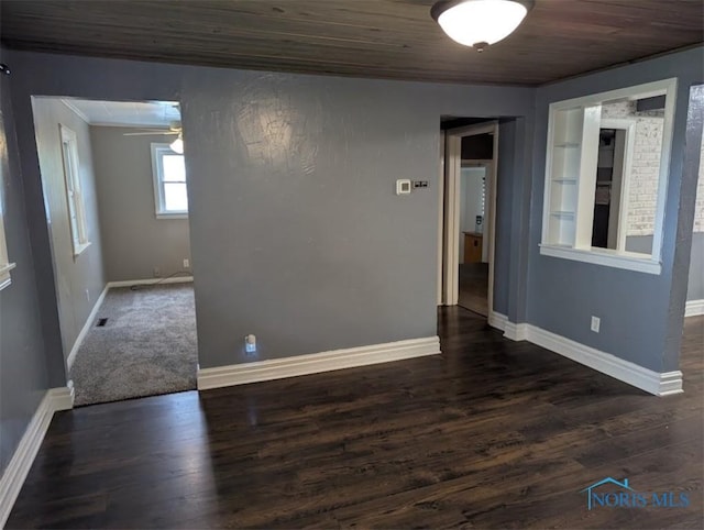 empty room featuring baseboards, ornamental molding, wood ceiling, and wood finished floors