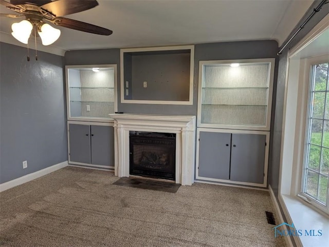 unfurnished living room featuring plenty of natural light, carpet, and baseboards