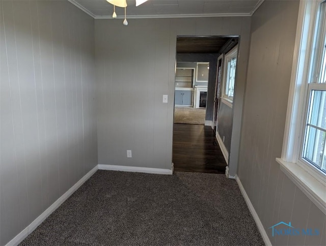 empty room featuring baseboards, ornamental molding, and carpet
