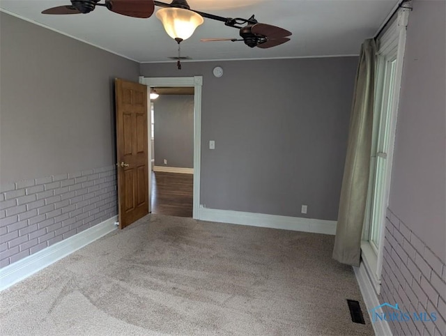 spare room featuring baseboards, ornamental molding, carpet, and ceiling fan