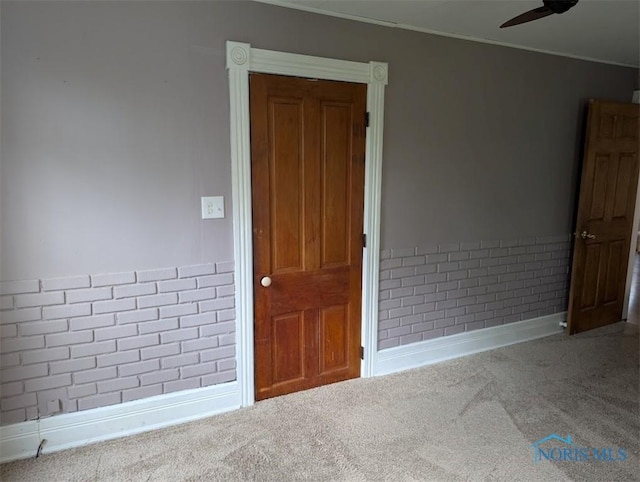 spare room featuring baseboards, carpet flooring, a ceiling fan, and crown molding
