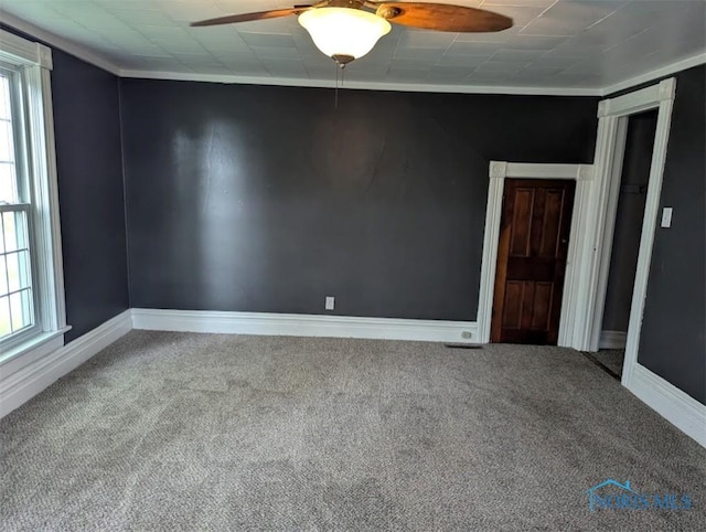 carpeted spare room featuring baseboards, ceiling fan, and a healthy amount of sunlight