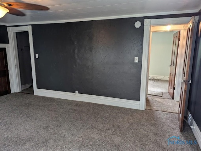 carpeted spare room featuring baseboards and ceiling fan