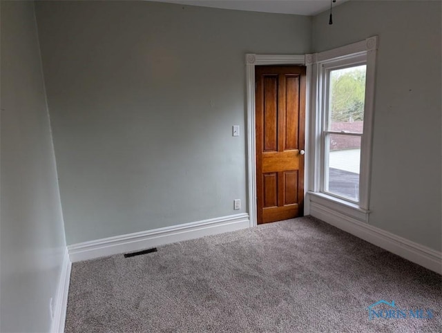 carpeted spare room featuring baseboards, plenty of natural light, and visible vents