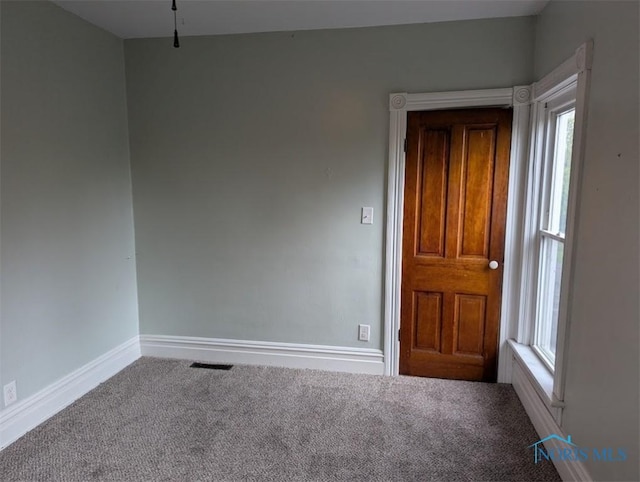 spare room featuring carpet floors, baseboards, and visible vents