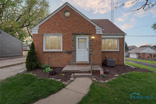 5583 304th St, Toledo, OH 43611 - bungalow-style house featuring a front lawn, brick siding, and central AC unit