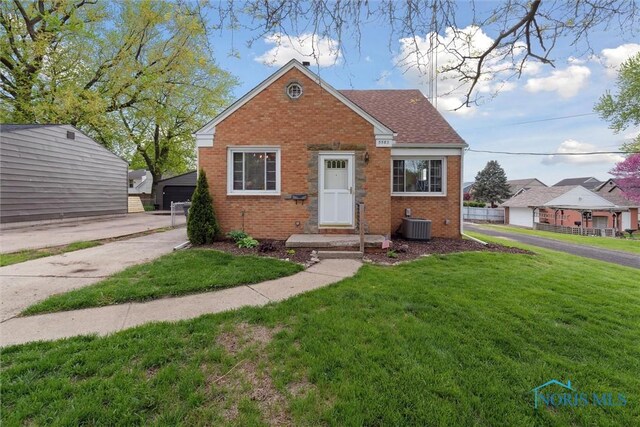 5583 304th St, Toledo, OH 43611 - view of front facade with a front lawn, brick siding, and cooling unit