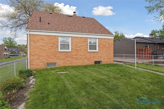 5583 304th St, Toledo, OH 43611 - back of house with a shingled roof, brick siding, a fenced backyard, and a yard
