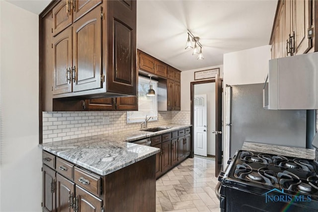 5583 304th St, Toledo, OH 43611 - kitchen with dark brown cabinets, a sink, tasteful backsplash, light stone counters, and gas stove