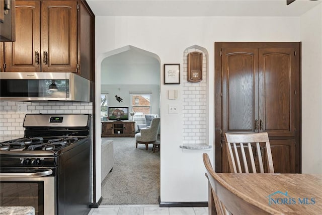 5583 304th St, Toledo, OH 43611 - kitchen featuring stainless steel appliances, light carpet, backsplash, arched walkways, and light countertops