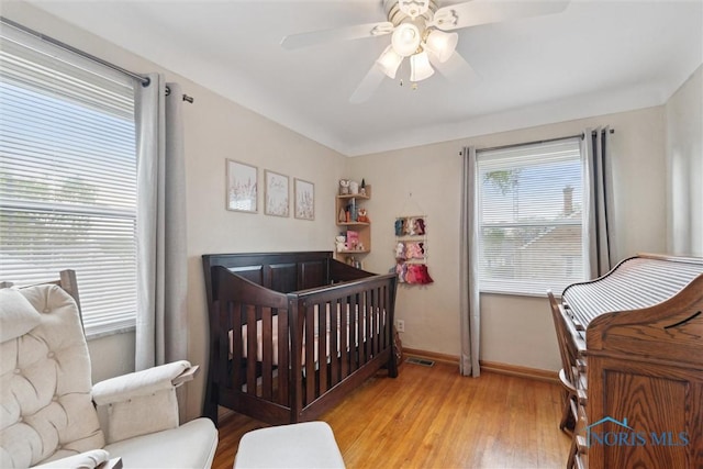 5583 304th St, Toledo, OH 43611 - bedroom featuring wood finished floors, visible vents, a ceiling fan, a crib, and baseboards