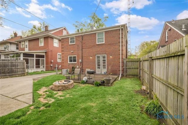 2923 Powhattan Pkwy, Toledo, OH 43606 - rear view of house featuring an outdoor fire pit, brick siding, cooling unit, a sunroom, and a patio area