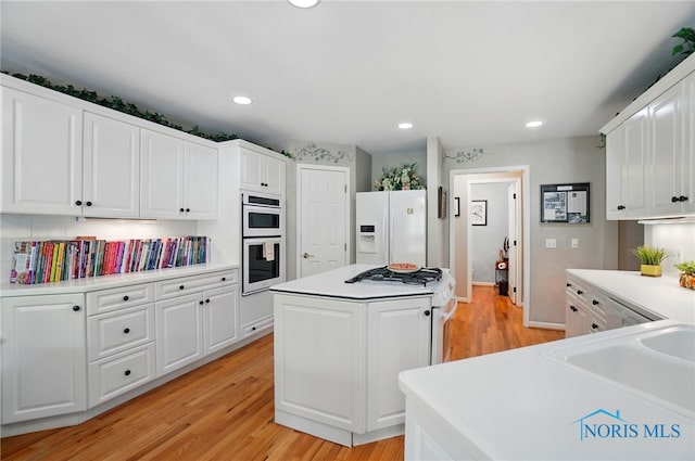 3145 Shoreland Ave, Toledo, OH 43611 - kitchen with white appliances, light wood-type flooring, a kitchen island, white cabinets, and recessed lighting