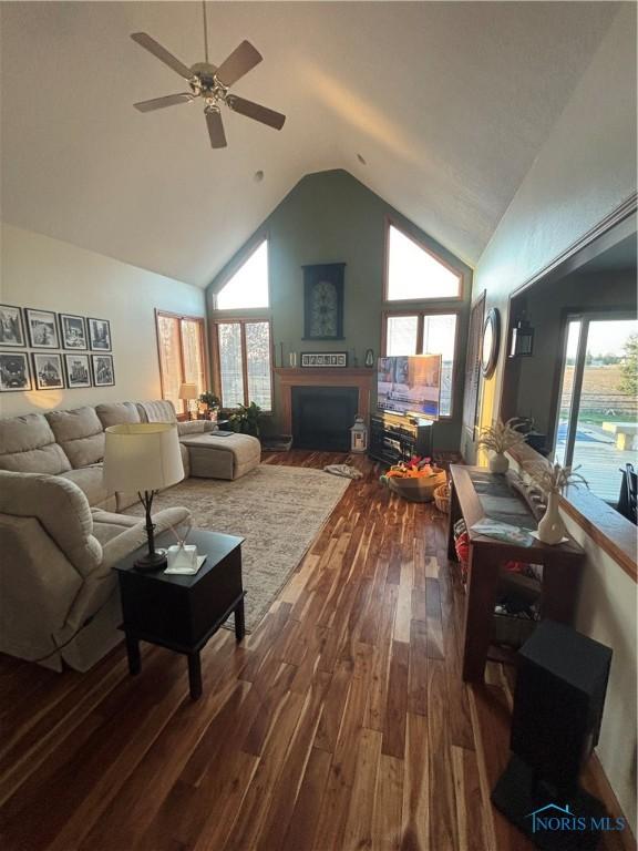 living room featuring dark wood-style floors, a ceiling fan, high vaulted ceiling, and a fireplace