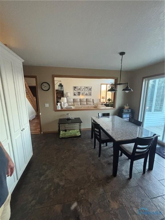 dining space featuring stairs, baseboards, and stone finish flooring