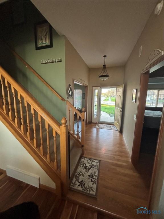 foyer entrance with baseboards, stairway, wood finished floors, and visible vents