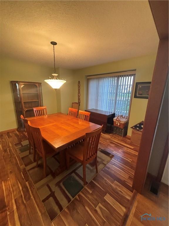 dining area with a textured ceiling and wood finished floors