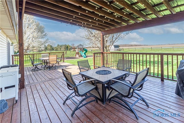 556 S Lathrop Rd, Swanton, OH 43558 - deck with a lawn, outdoor dining space, a playground, and a fenced backyard