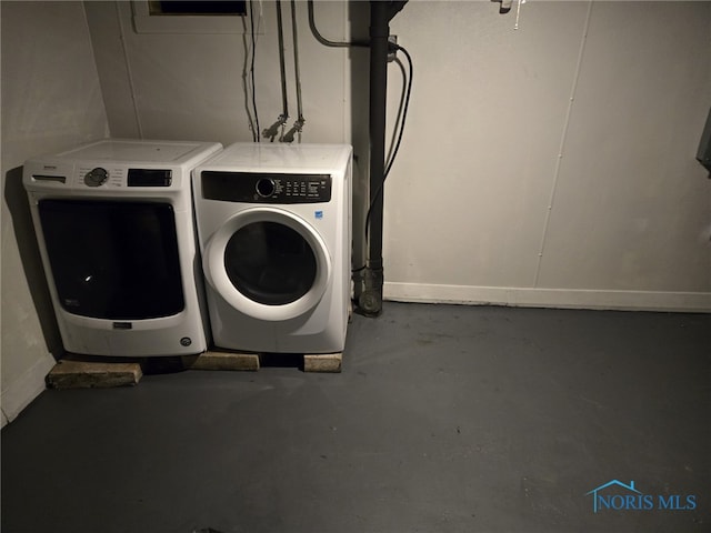 washroom featuring baseboards, washing machine and clothes dryer, and laundry area