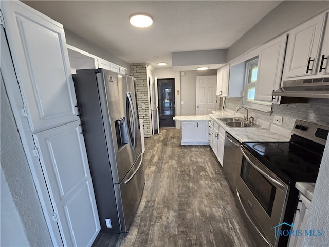 kitchen with under cabinet range hood, appliances with stainless steel finishes, a sink, white cabinetry, and dark wood-type flooring