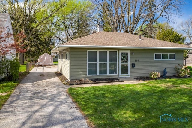 back of house with a lawn, a chimney, aphalt driveway, and a shingled roof