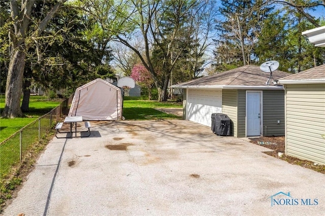 view of patio with fence, a garage, and an outbuilding