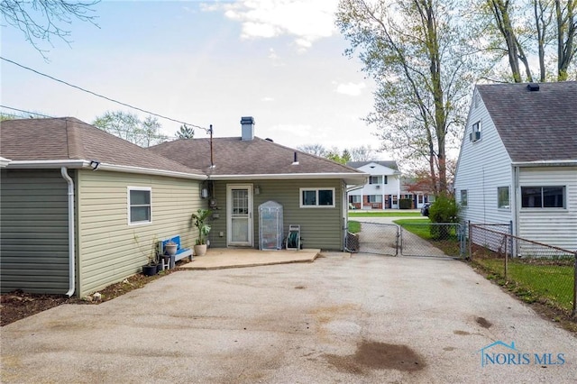 back of property with a patio, a gate, driveway, a chimney, and fence