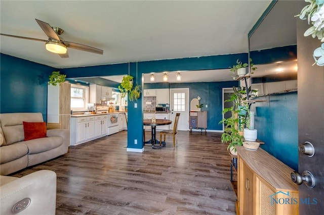 living area featuring a healthy amount of sunlight, baseboards, wood finished floors, and ceiling fan