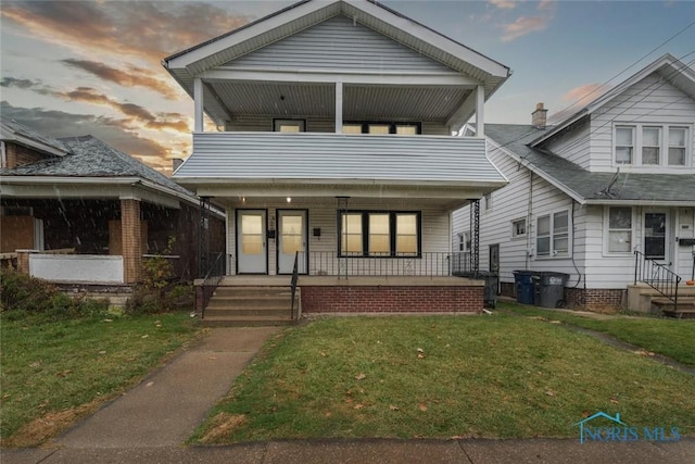 view of front of house with a porch, a front lawn, and a balcony