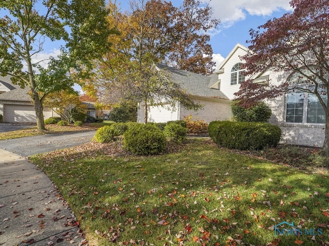 view of side of property featuring brick siding, a yard, and an attached garage
