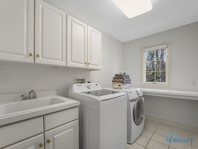 washroom with a sink, cabinet space, washing machine and clothes dryer, light tile patterned floors, and baseboards