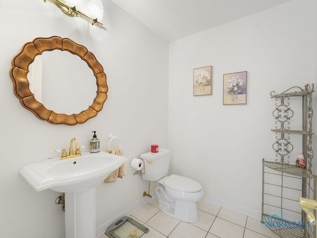 half bath with tile patterned floors, toilet, and baseboards