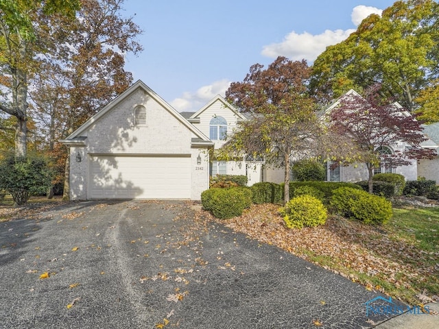 view of front of home with driveway, an attached garage, and brick siding