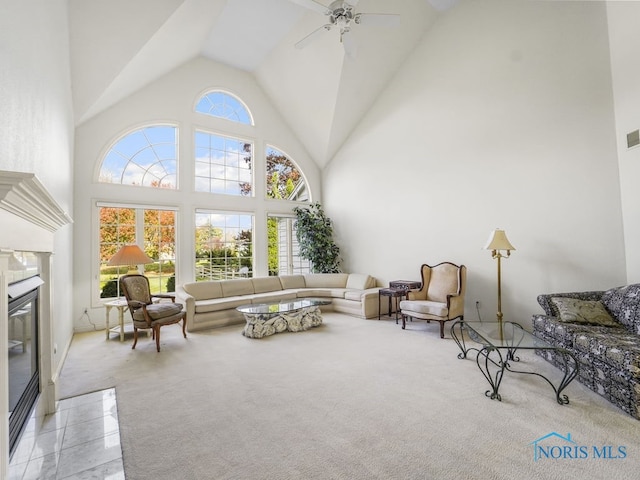 carpeted living room with a ceiling fan, high vaulted ceiling, visible vents, and a fireplace