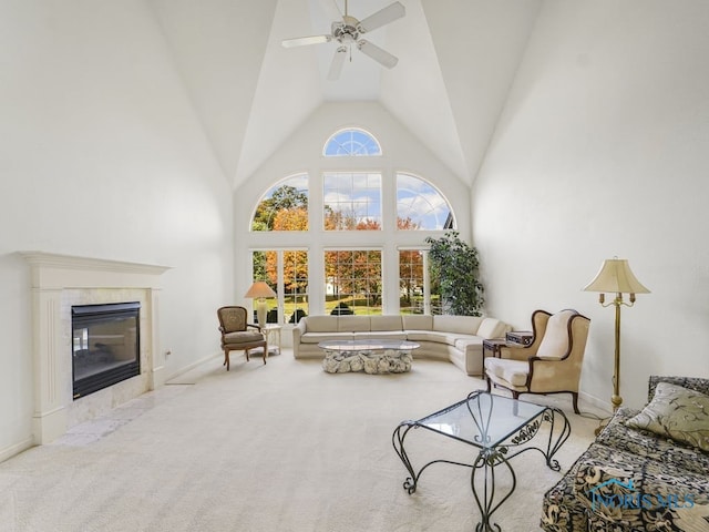carpeted living room with baseboards, high vaulted ceiling, ceiling fan, and a fireplace