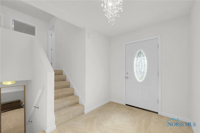 foyer entrance featuring an inviting chandelier, stairs, carpet, and baseboards
