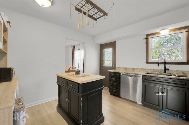 kitchen with a sink, dishwasher, dark cabinets, light wood-style flooring, and a wealth of natural light