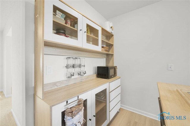 interior space with black microwave, baseboards, and light wood finished floors