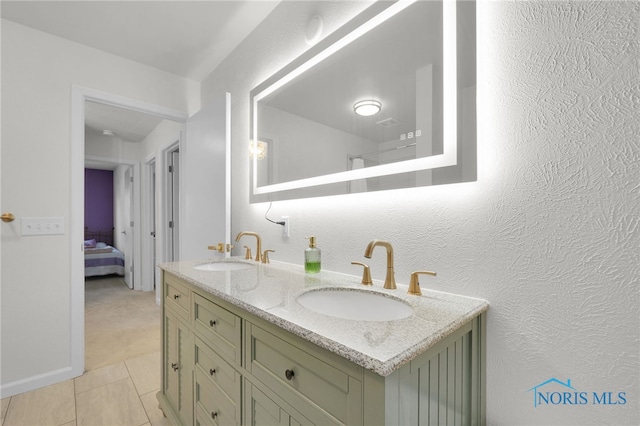 ensuite bathroom featuring double vanity, tile patterned floors, a sink, and ensuite bathroom