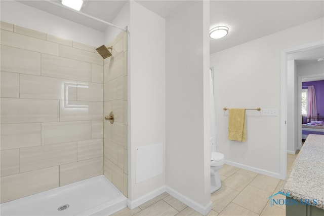 bathroom featuring toilet, tiled shower, and tile patterned flooring