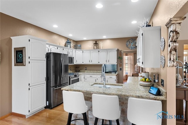 6170 S Winding Way, Swanton, OH 43558 - kitchen with light stone countertops, a sink, stainless steel appliances, light wood-type flooring, and a peninsula