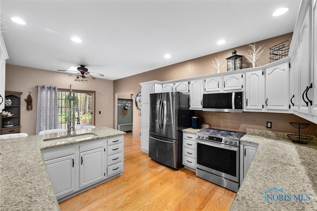 6170 S Winding Way, Swanton, OH 43558 - kitchen with white cabinetry, light wood-style flooring, a sink, stainless steel appliances, and a ceiling fan