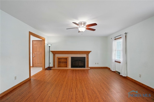 864 Cherry Ln, Waterville, OH 43566 - unfurnished living room featuring light wood-style flooring, a glass covered fireplace, a ceiling fan, and baseboards