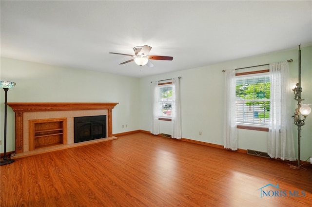 864 Cherry Ln, Waterville, OH 43566 - unfurnished living room with wood finished floors, a ceiling fan, a tiled fireplace, and baseboards